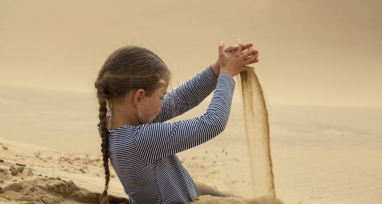 Kind dat speelt met zand in een woestijnlandschap.