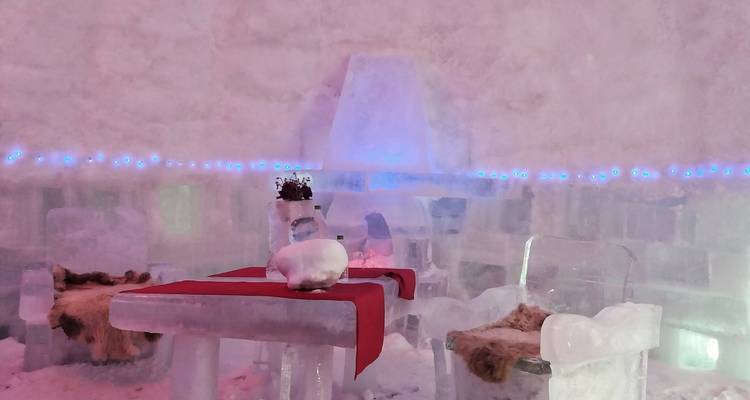 Interieur van een iglo gemaakt van ijs met een tafel en stoelen.