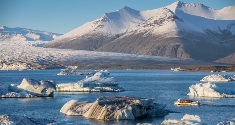Icebergs floating on a glacier lagoon with mountains in the background.