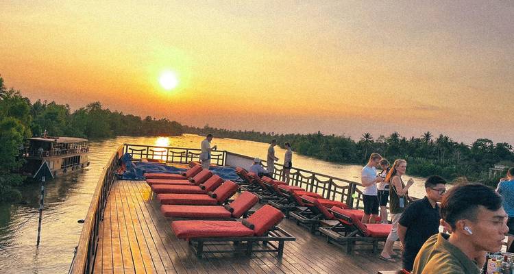 Des gens sur un bateau profitant d'un coucher de soleil sur une rivière.