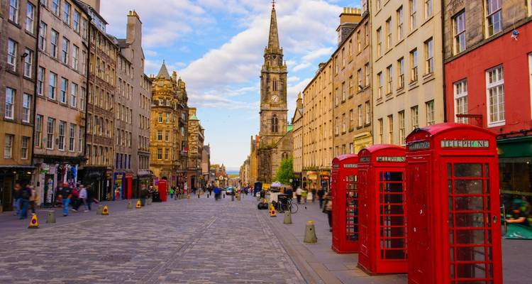 Bulliciosa calle Royal Mile con edificios históricos, cabinas telefónicas rojas y peatones en Edimburgo