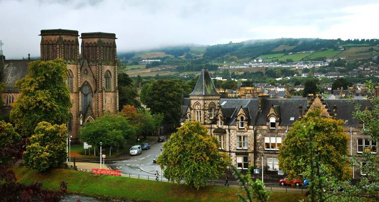 Vista matutina brumosa de Inverness con torres de catedral y colinas ondulantes al fondo