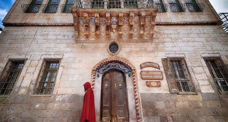 Persoon die voorbij een sierlijk oud gebouw loopt met een grote deur.