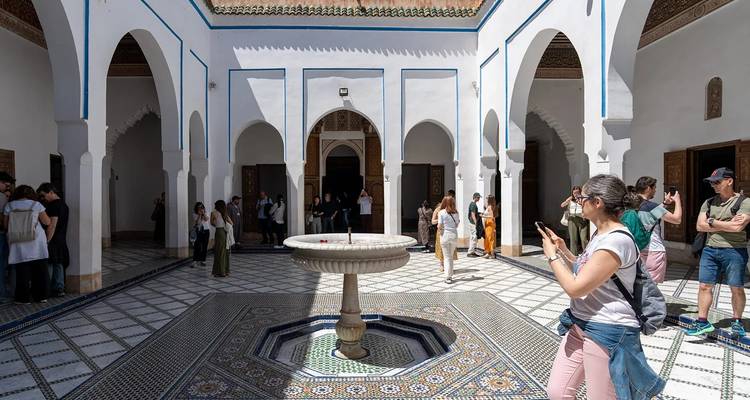 Des touristes explorant une cour marocaine carrelée.