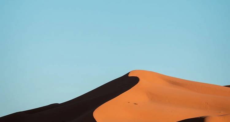 Silhouette of a dune under a clear sky.