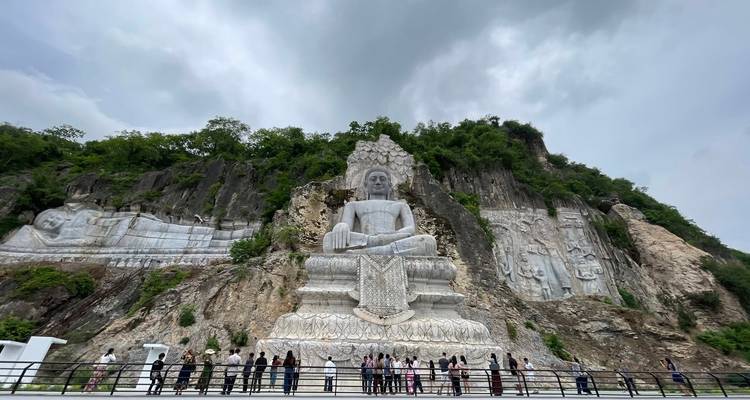Large Buddha statues carved into a cliff with spectators.