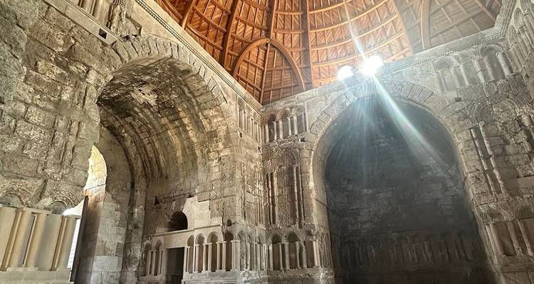 Interior of a stone building with arches and natural light.