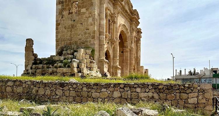 Side view of an ancient stone arch with ruins in the foreground.