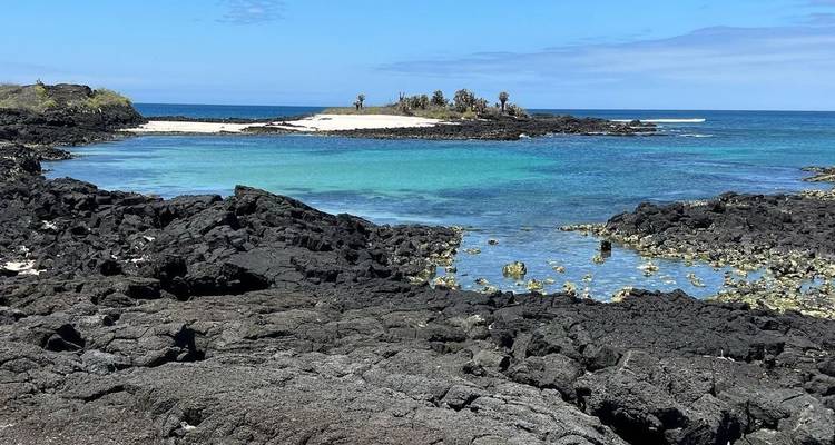 Une plage immaculée avec une eau turquoise et des formations rocheuses volcaniques.