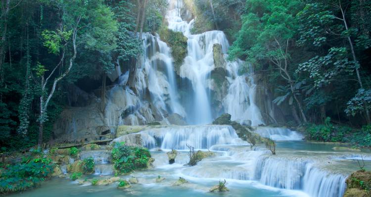Cascade de cascade tropicale multi-étages descendant à travers une jungle dense et verdoyante dans des bassins d'eau émeraude.