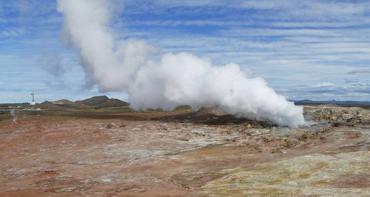 Geysir, der Dampf in den Himmel speit in einer kargen Landschaft.