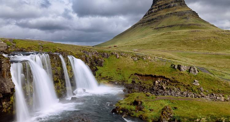 Wasserfall, der neben einem markanten Berg fließt.