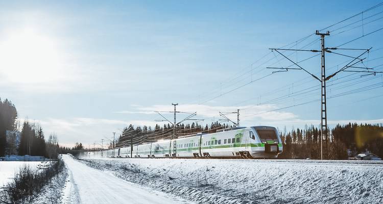 Un train moderne traversant un paysage enneigé avec des pins.