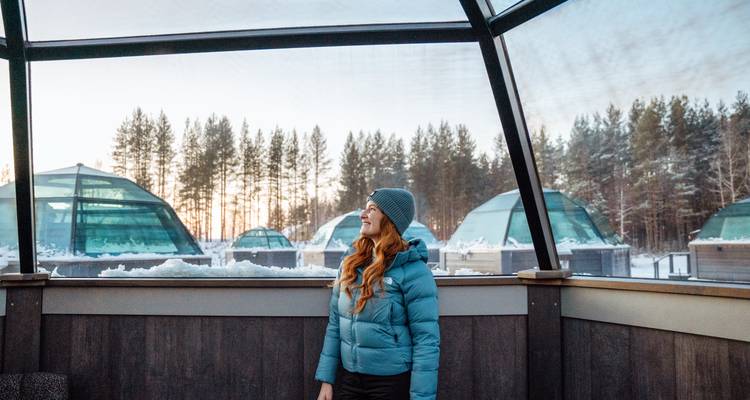 Une personne profitant de la vue depuis un igloo de verre entouré de neige.