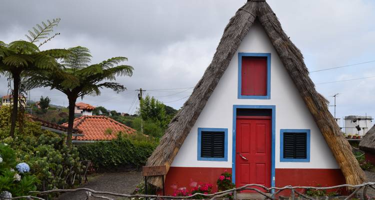 Maison traditionnelle en forme de A avec un design coloré et un jardin luxuriant.