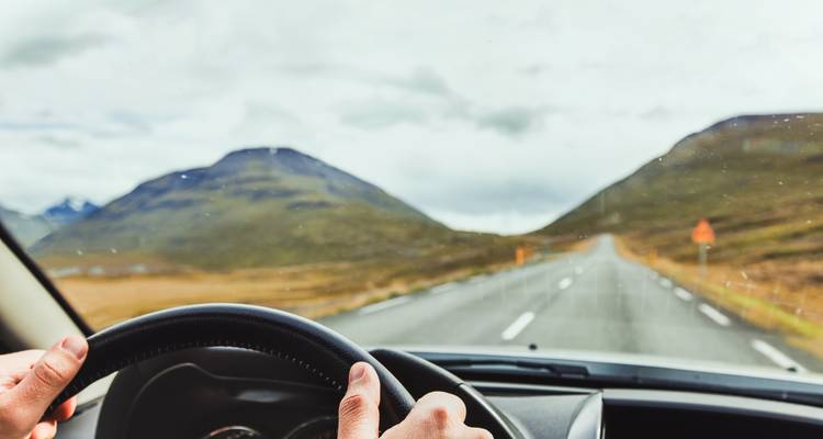 View from a car dashboard while driving on a scenic road.