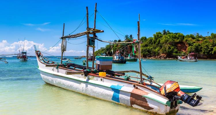 Traditionelles Fischerboot auf einem klaren blauen Meer mit anderen Booten im Hintergrund.