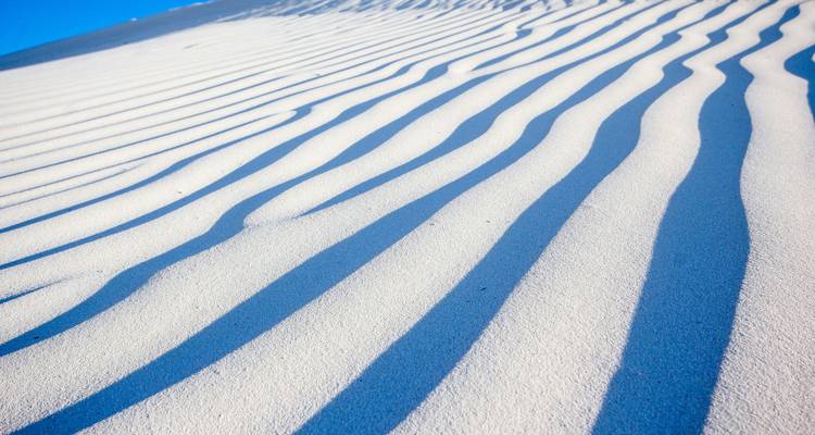 Dune de sable avec la lumière du soleil créant des ombres à travers les ondulations.