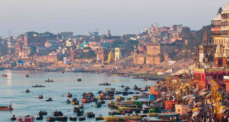Kleurrijke ghats langs de rivieroever in Varanasi met boten.