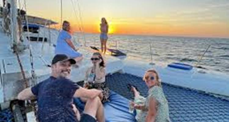 Groep mensen op een boot tijdens zonsondergang.