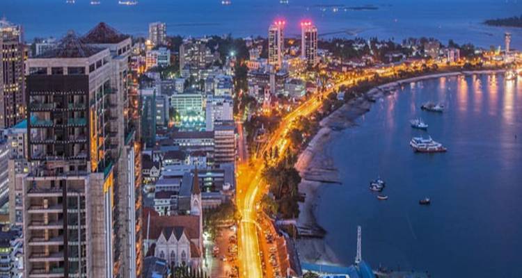 Stadsgezicht bij nacht met verlichte wegen en gebouwen aan zee.