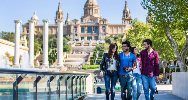 Groupe d'amis marchant devant les fontaines en direction du grand Palau Nacional sur la colline de Montjuïc à Barcelone.