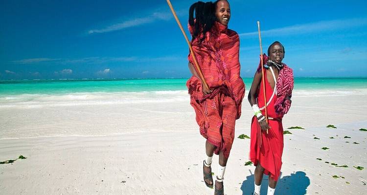 Masai mannen die springen op een strand met blauwe luchten.
