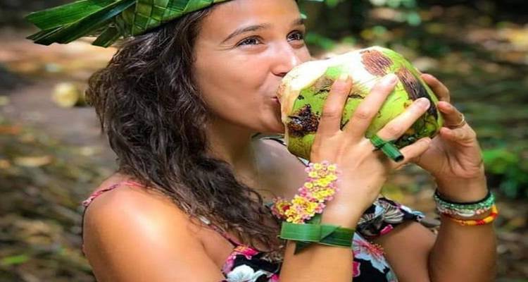 Femme sirotant dans une noix de coco avec un chapeau en feuille.