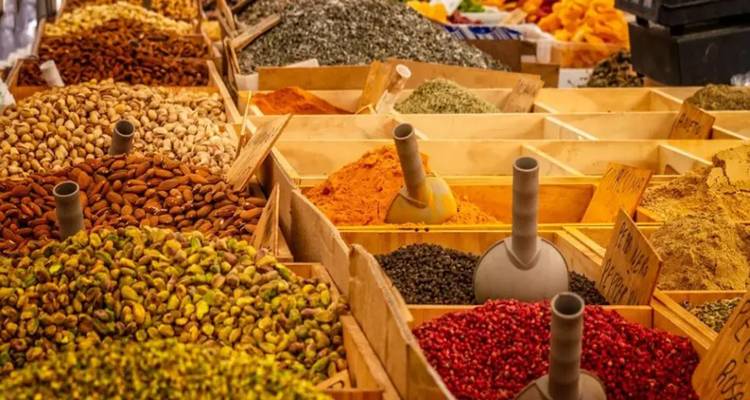 Un étalage coloré de diverses épices sur un marché, organisées dans des compartiments en bois.