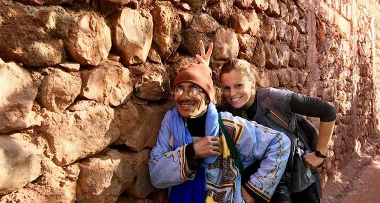 Two people posing against a rocky wall, smiling.