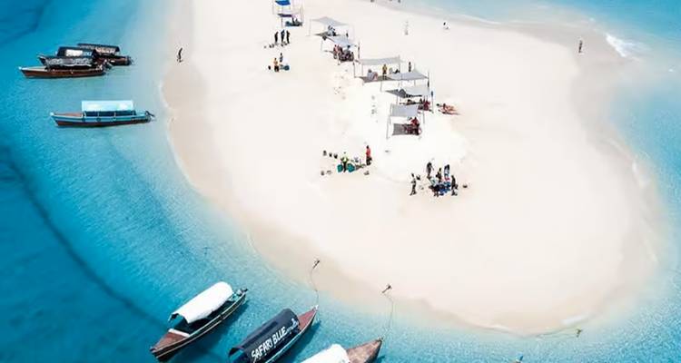 Luchtfoto van een zandbank met mensen en boten op helder blauw water.