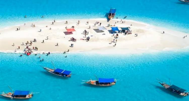 Zandbank omgeven door blauwe oceaan, met mensen en boten.