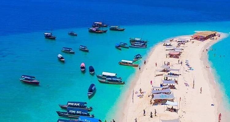 Talloze boten rond een zandbank met tenten en zonnebaders.