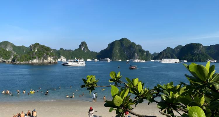 Plage avec touristes et bateaux profitant de la baie d'Halong.