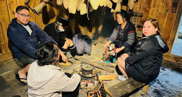 Des gens assis autour d'un feu dans un cadre rustique, à l'intérieur.