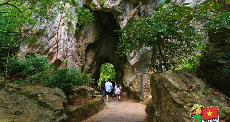 Des personnes marchant à travers une arche de pierre naturelle dans un cadre verdoyant luxuriant.
