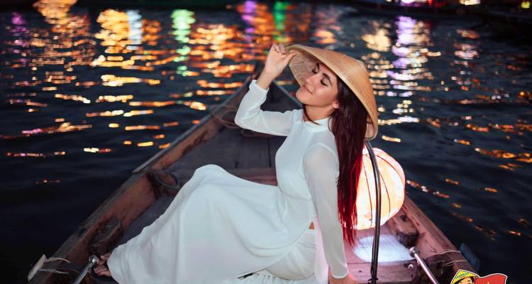 Personne dans un bateau sur une rivière la nuit avec des reflets illuminés.