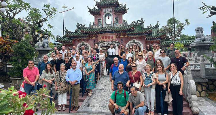 Gran grupo turístico internacional reunido en las escaleras del ornamentado Salón de Asambleas de Fujian en Hoi An.