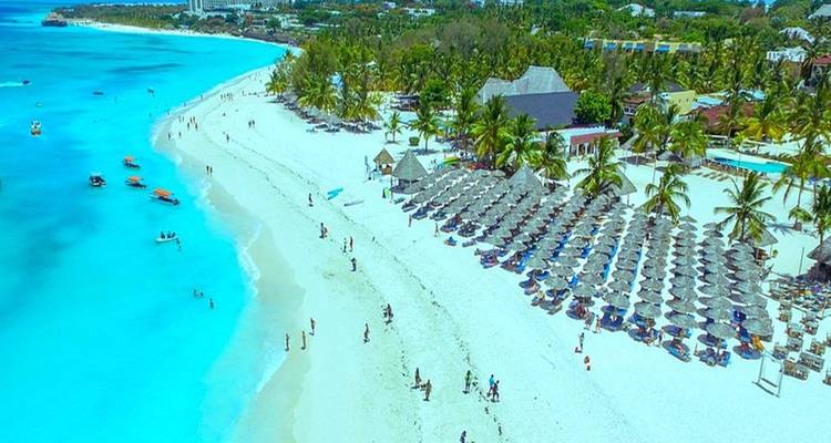 Luftaufnahme eines Strandes mit Sonnenschirmen und Gebäuden