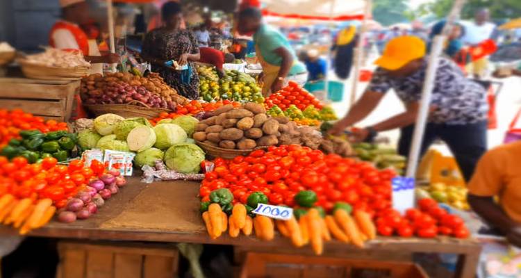 Ein bunter Marktstand mit einer Vielfalt an frischem Gemüse, darunter Tomaten, Kartoffeln und Paprika.