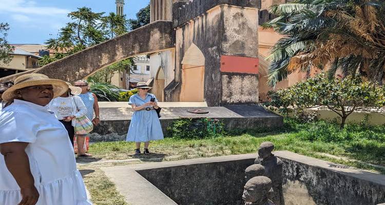 Touristen stehen in der Nähe eines historischen Gebäudes und Skulpturen.