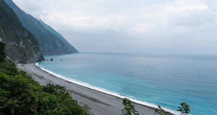 Küstenblick mit einem Strand und Klippen, die auf das Meer treffen.