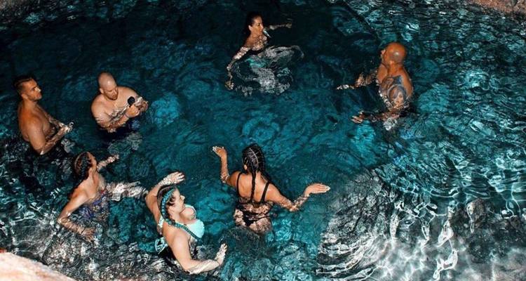 Group of people swimming in a clear blue pool.