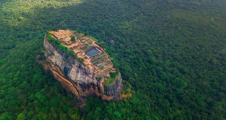 Aerial view of Sigiriya Rock Fortress amidst lush green forest.