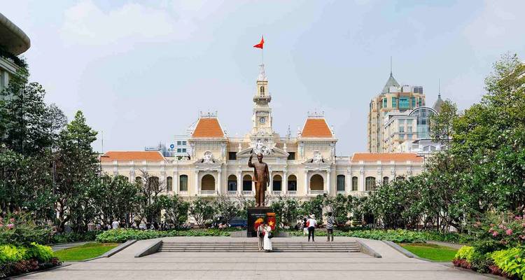Het elegante Frans-koloniale stadhuis van Ho Chi Minh met verzorgde tuinen en een Vietnamese vlag die erboven wappert.