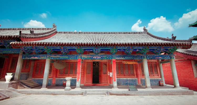 Colorful ancient Chinese hall with richly painted beams under bright skies.