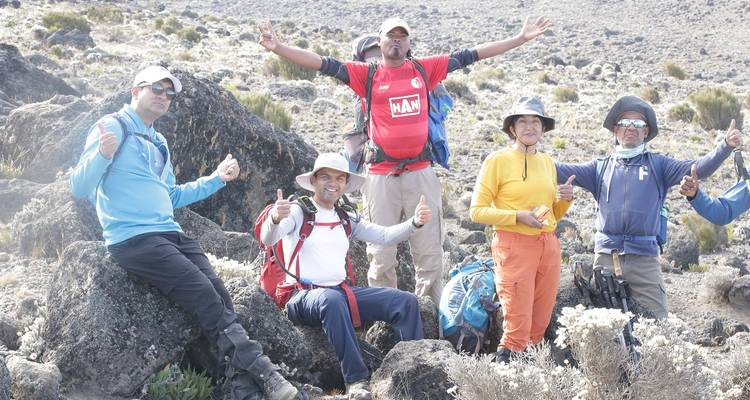 Group of hikers posing on a rocky terrain in casual clothing.