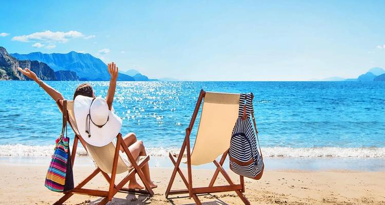 Two lounge chairs facing the ocean on a sunny day.