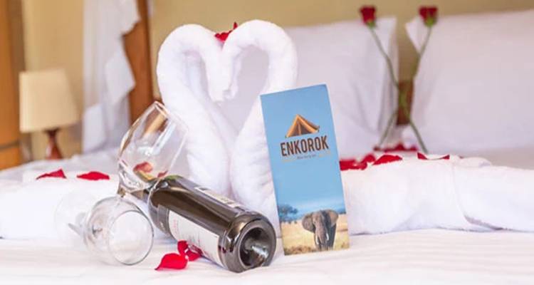 Netjes opgemaakt hotelbed met wijnfles en glazen.