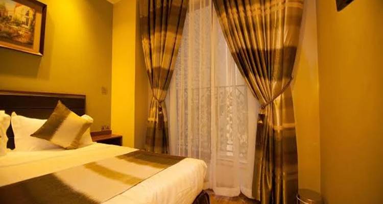 Interieur van een hotelkamer met een bed en gesloten gordijnen.